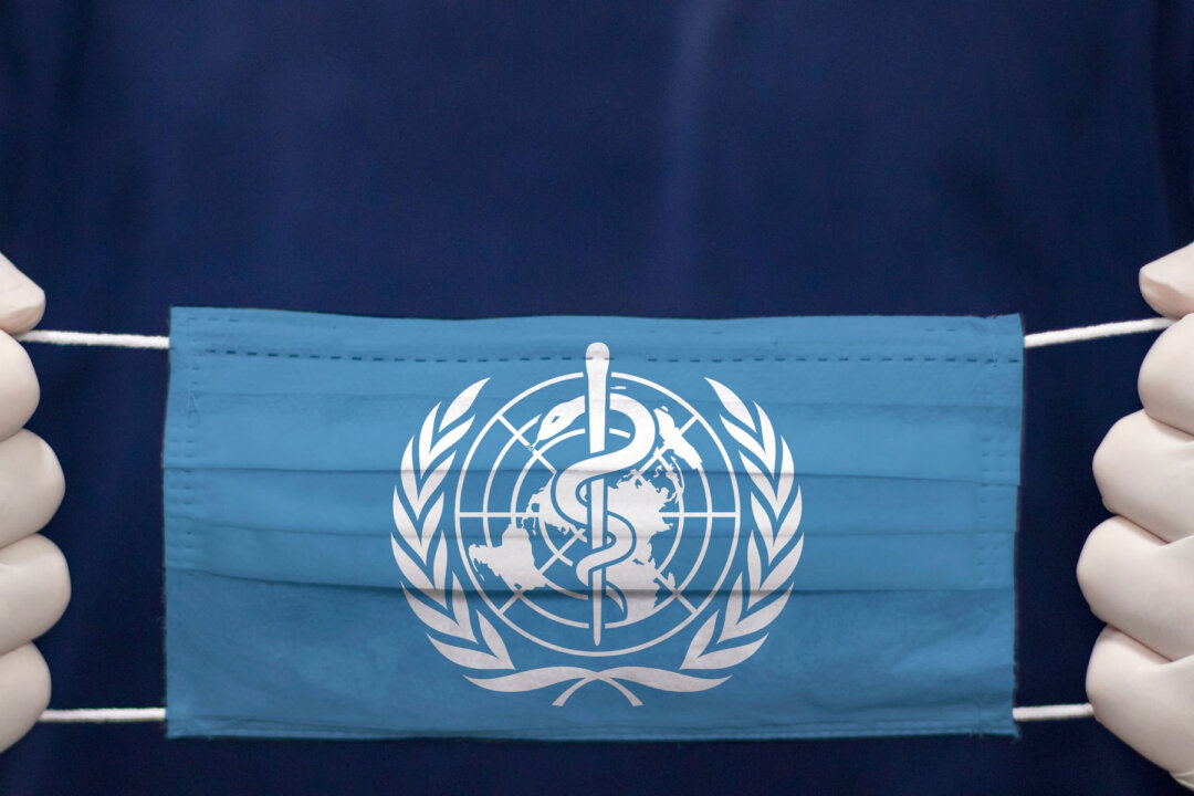 Một bác sĩ cầm chiếc khẩu trang y tế in cờ của Tổ chức Y tế Thế giới. (Ảnh: kcube-Baytur/Shutterstock)