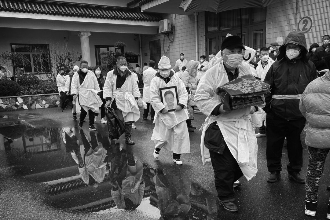 Một người đưa tang ôm hộp hài cốt đã hỏa táng của người thân khi ông cùng thân quyến mặc đồ tang màu trắng truyền thống, trong một đám tang ở Thượng Hải, Trung Quốc, vào ngày 14/01/2023. (Ảnh: Kevin Frayer/Getty Images)